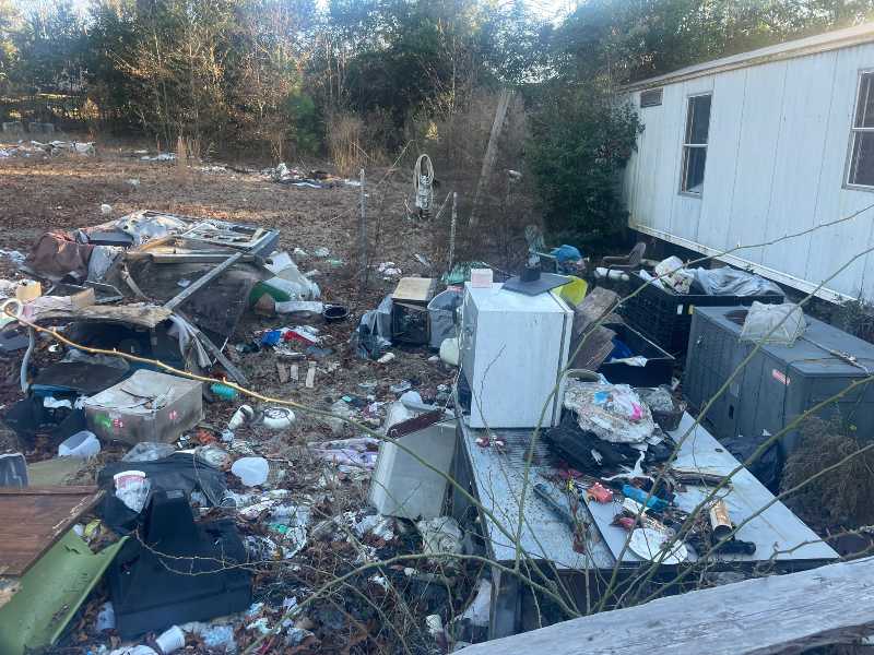 Shown is a picture of the exterior of a hoarder house cleanout in Augusta Georgia. Debris and waste is scattered throughout the property